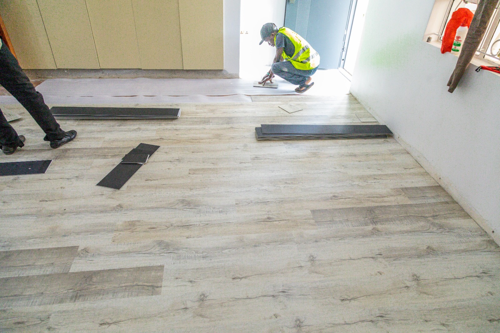 Grey oak SPC laminate floor mid-installation in a kitchen